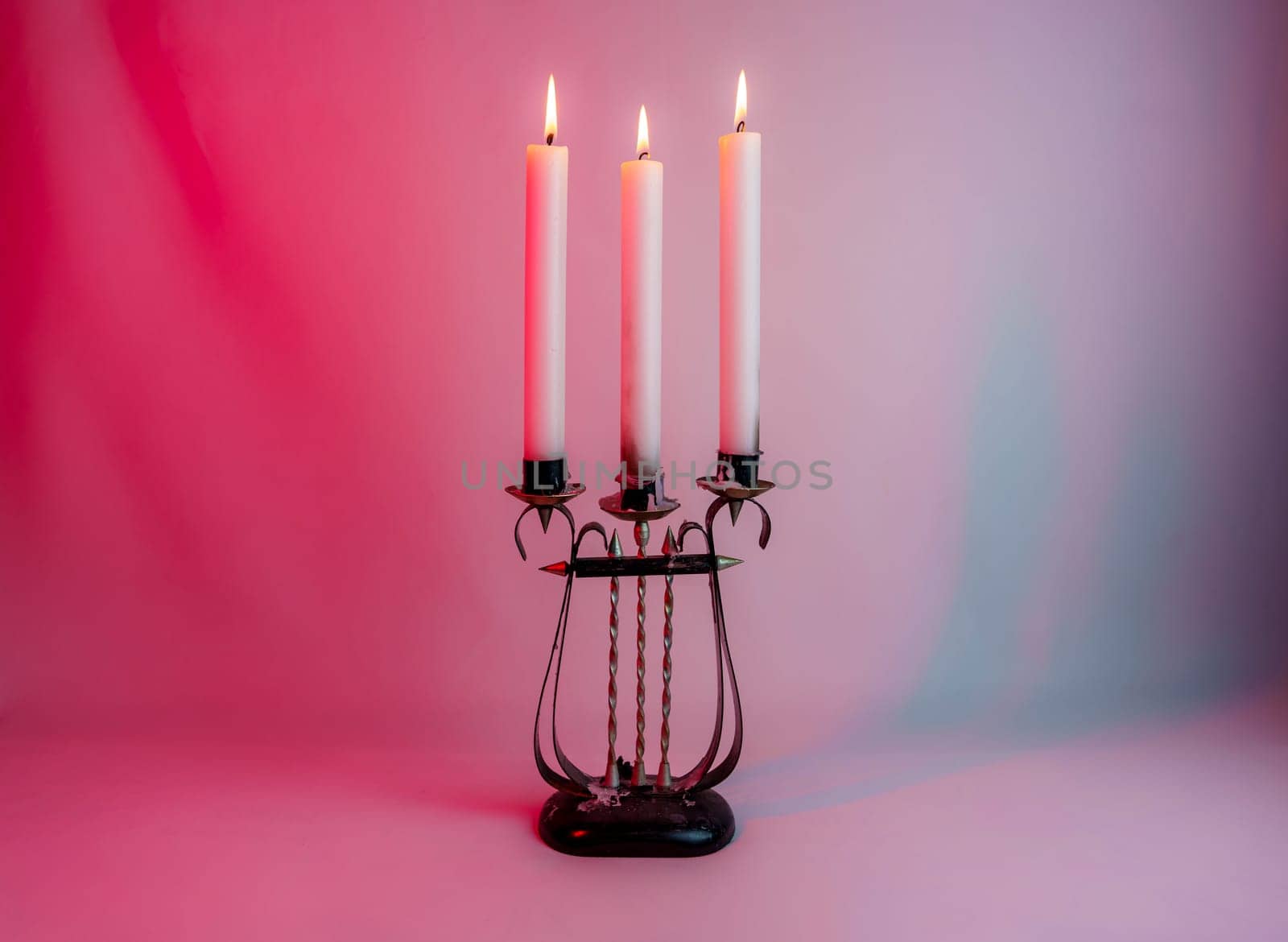 Elegant antique candelabrum with three lit candles, casting a warm glow on a red and purple gradient background. Perfect for romantic, gothic, and vintage-themed designs