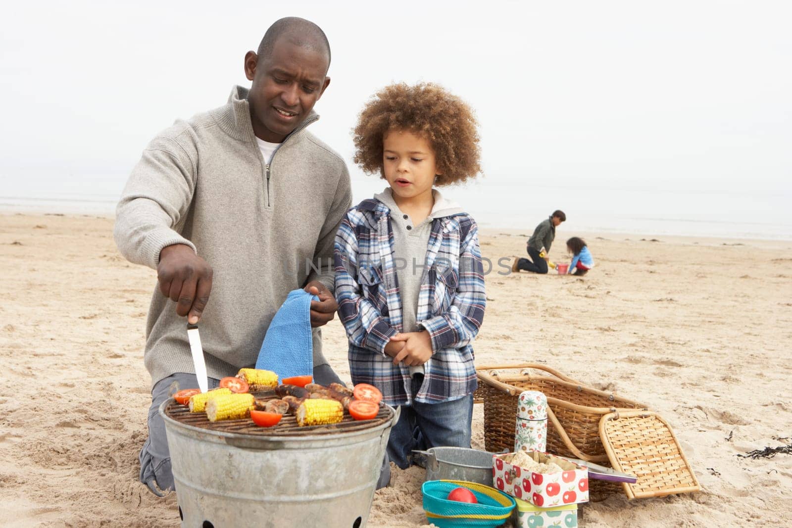 Young Family Enjoying Barbeque On Beach