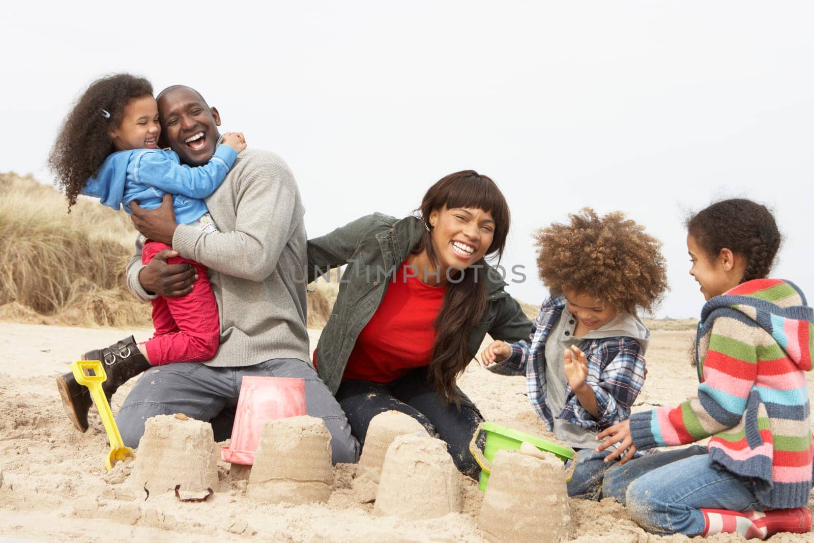 Young Family Building Sandcastle On Beach Holiday