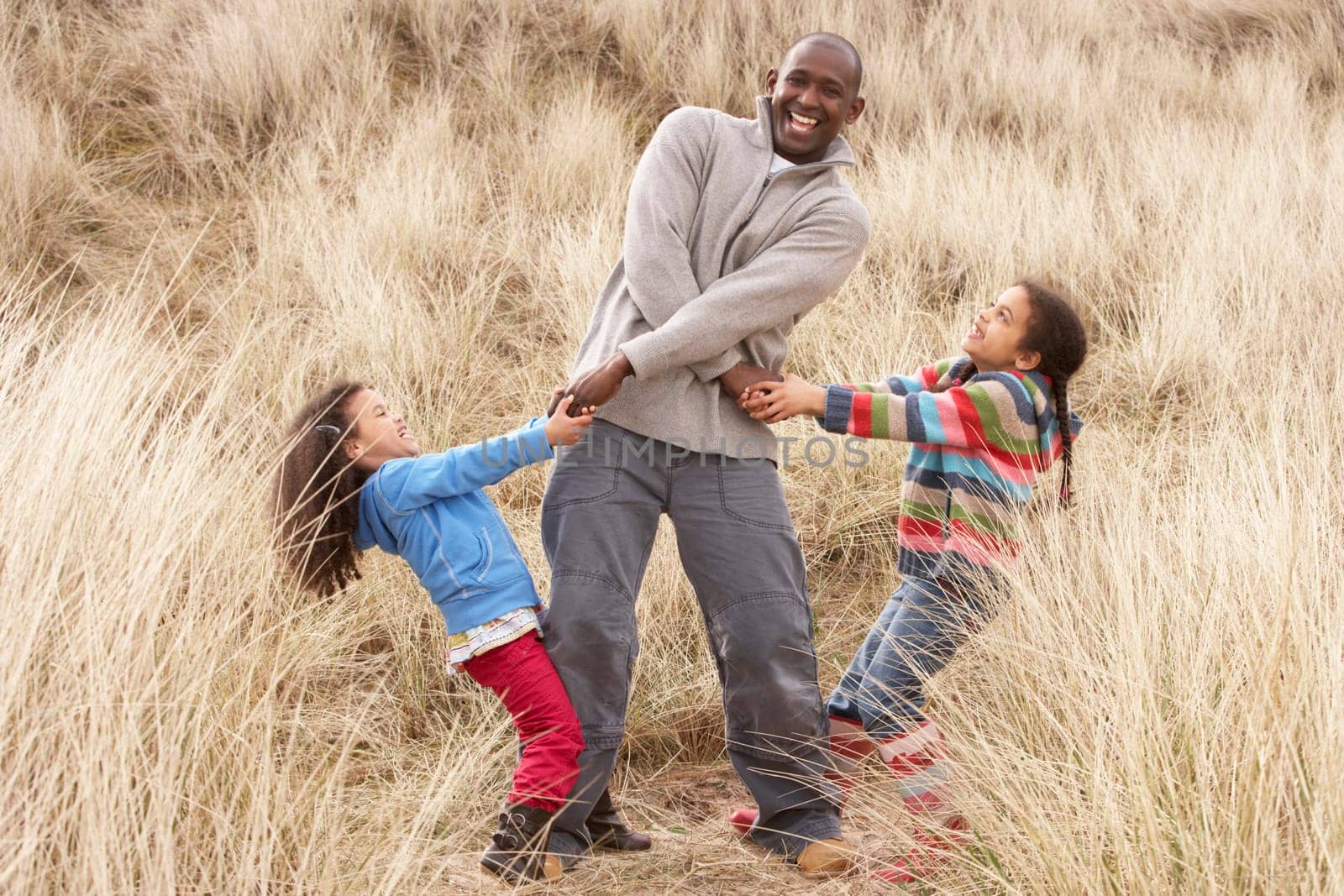 Father And Daughters Having Fun In Sand Dunes