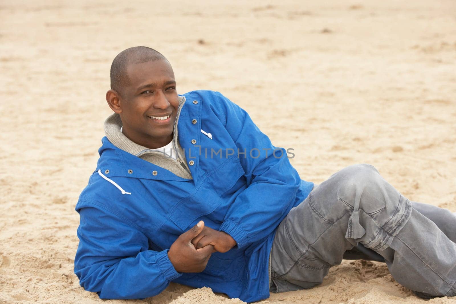 Man Relaxing On Beach In Autumn Clothing