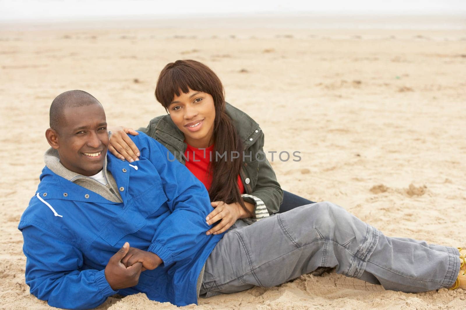 Young Couple Relaxing On Winter Beach Holiday