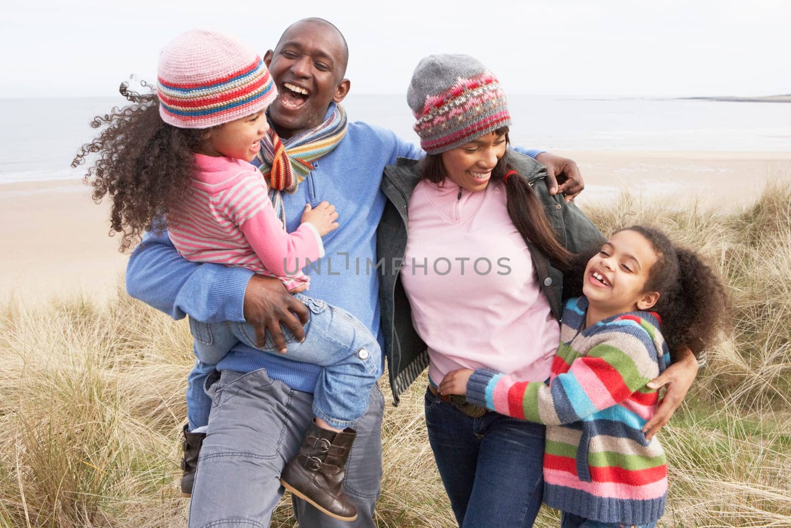 Family Walking Along Dunes On Winter Beach