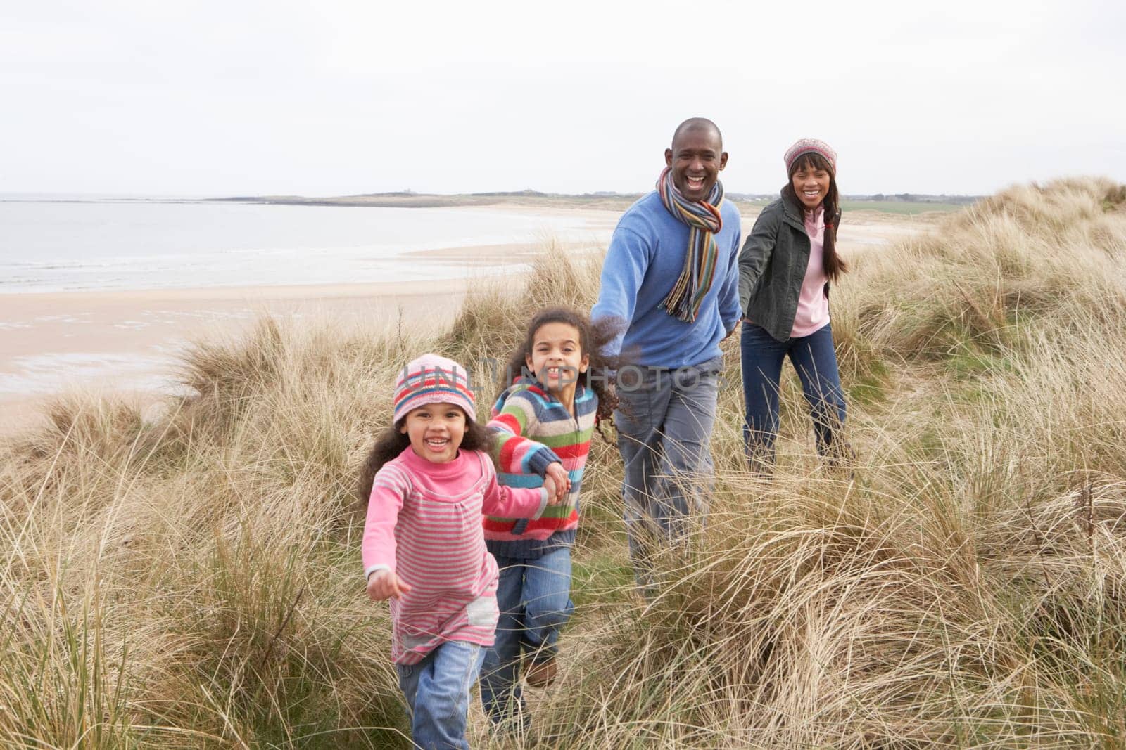 Family Walking Along Dunes On Winter Beach