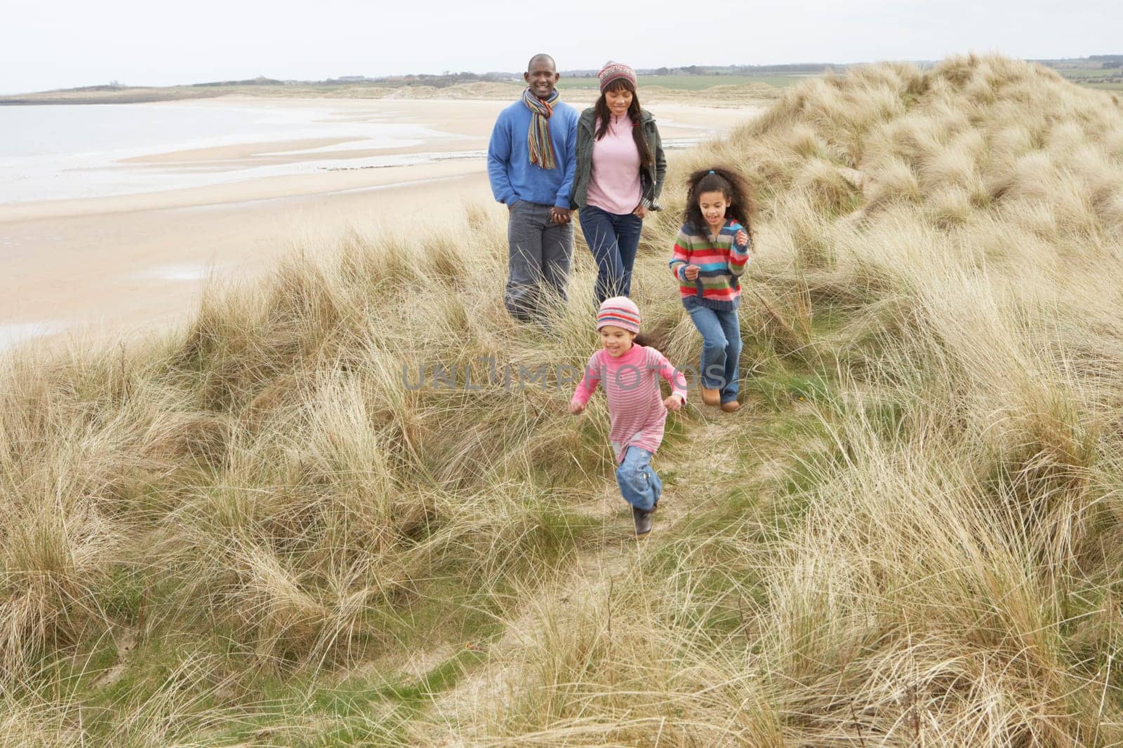 Family Walking Along Dunes On Winter Beach