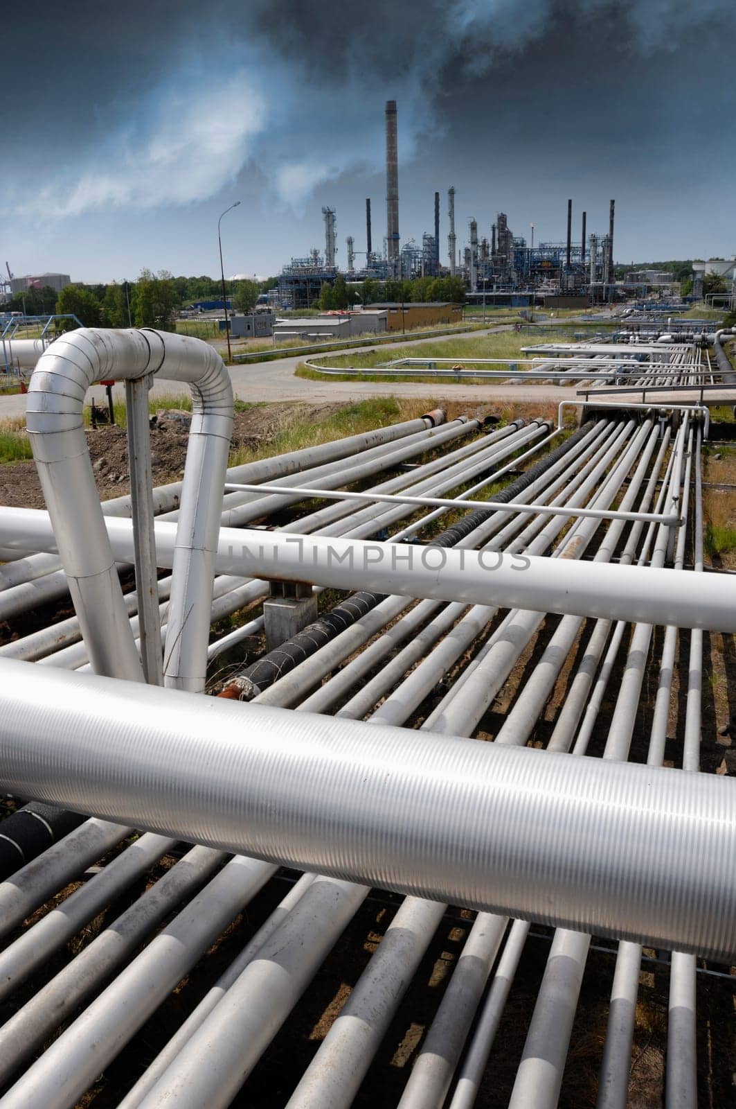 pipelines construction leading to refinery, dark storm clouds moving in over industry