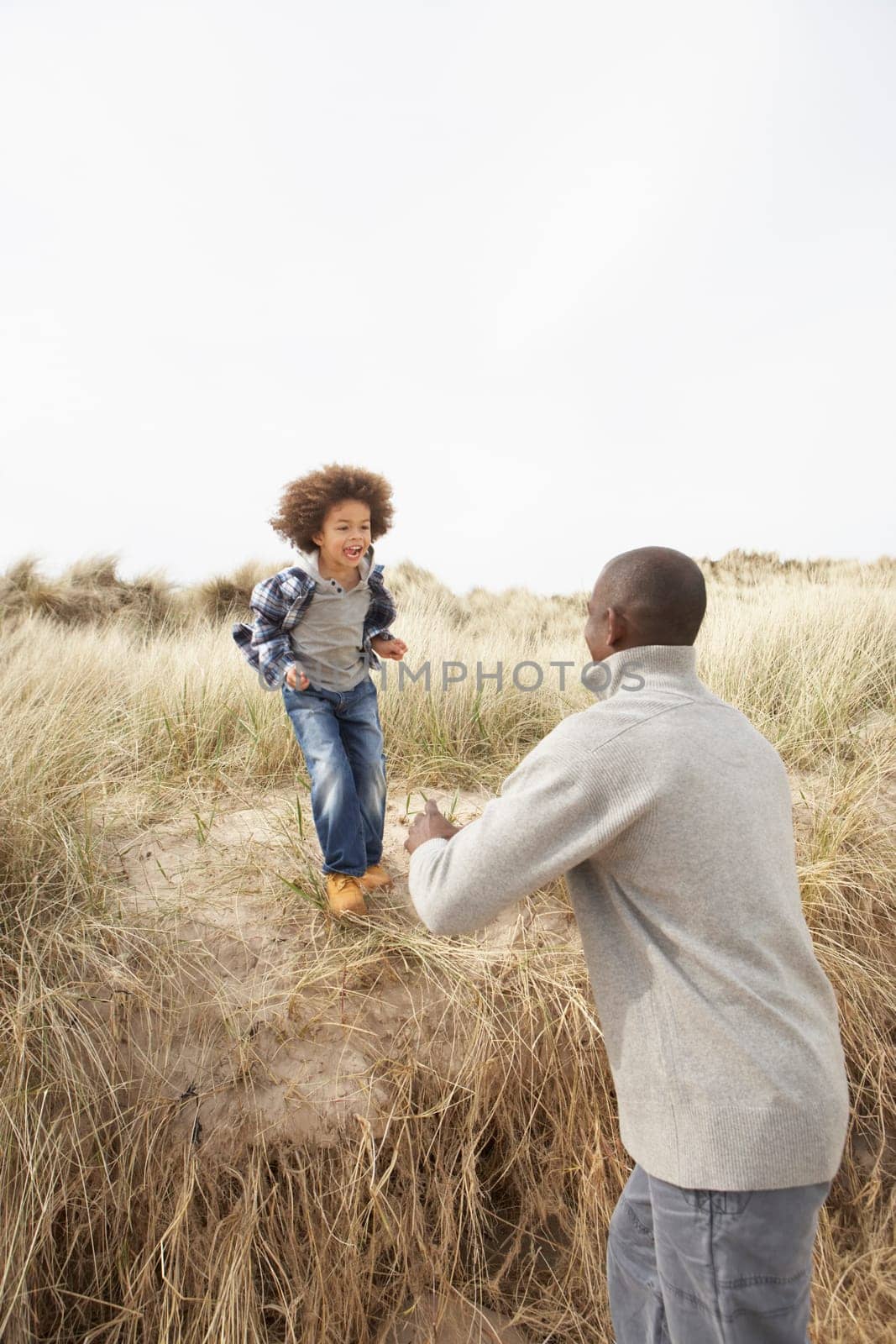 Father And Son Having Fun In Sand Dunes