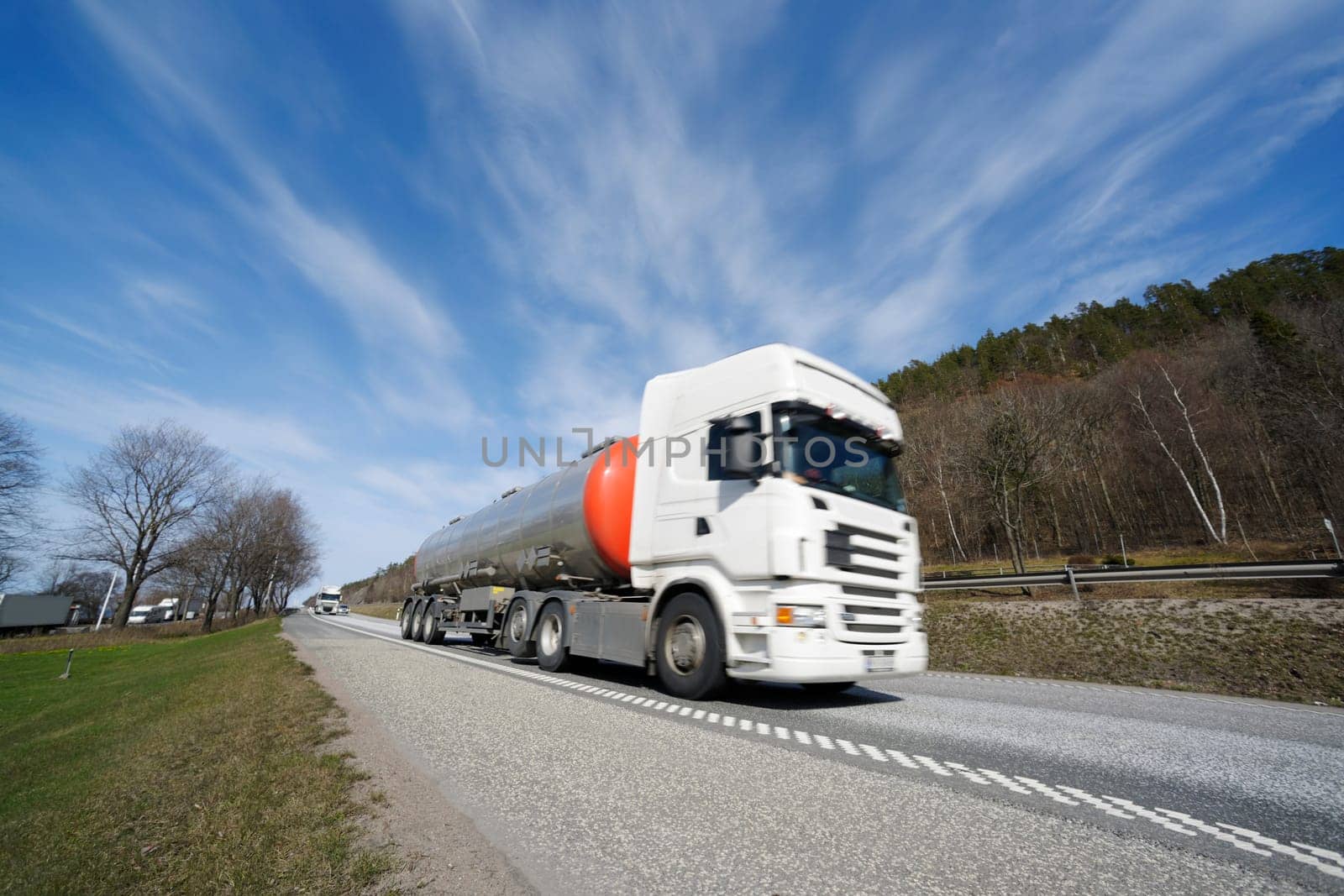 fuel-truck in speedy motion, blurred, driving on scenic highway, ground level perspective
