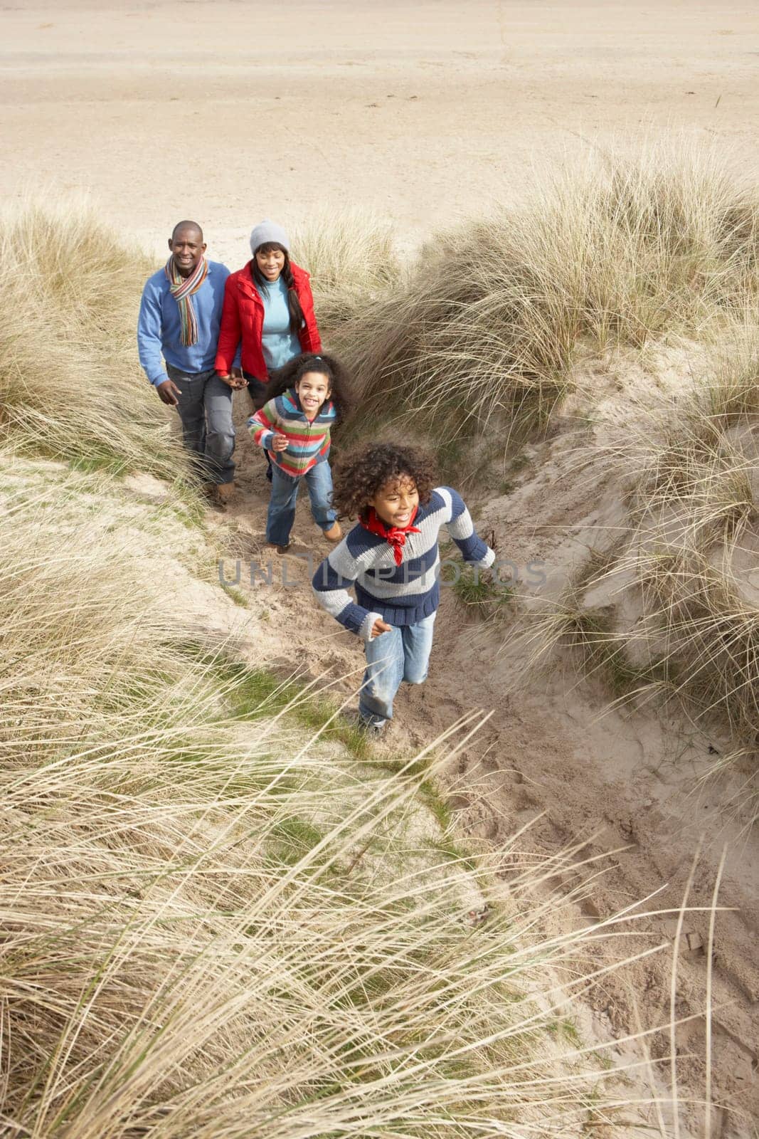 Family Walking Along Dunes On Winter Beach