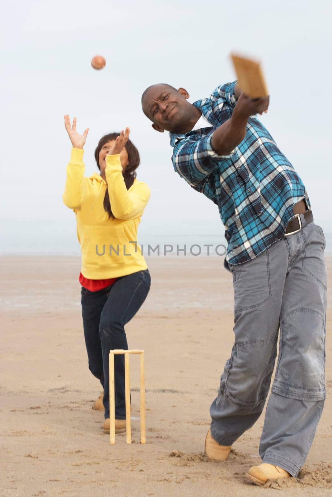 Young Couple Playing Cricket On Autumn Beach Holiday