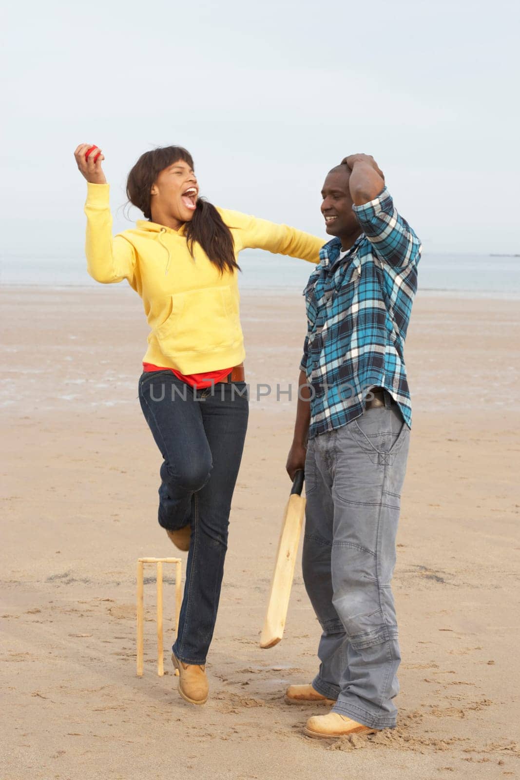 Young Couple Playing Cricket On Autumn Beach Holiday