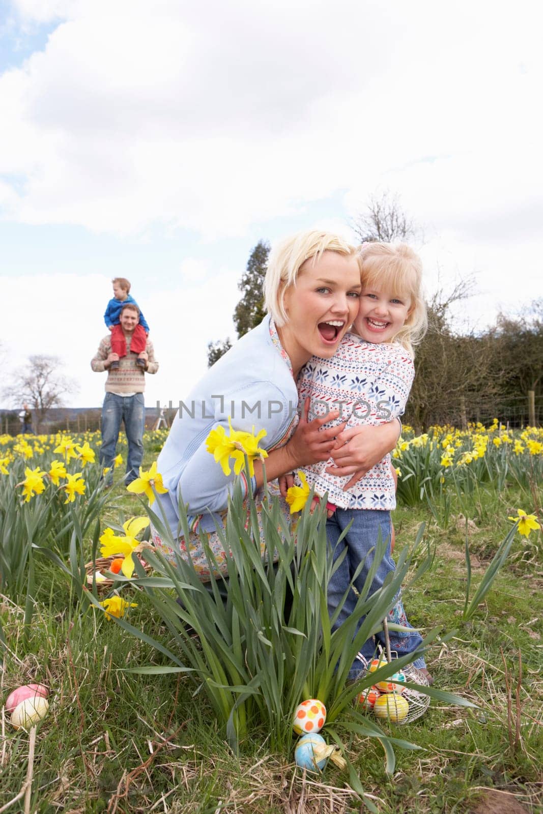 Family On Easter Egg Hunt In Daffodil Field
