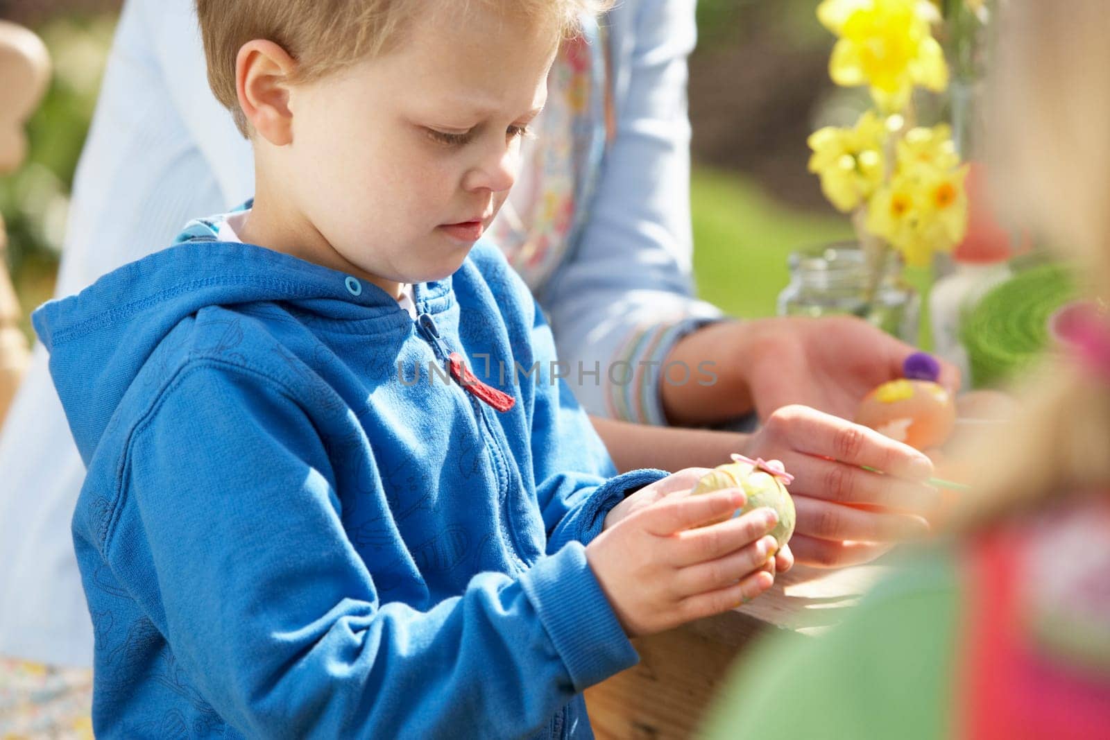 Mother And Children Decorating Easter Eggs On Table Outdoors