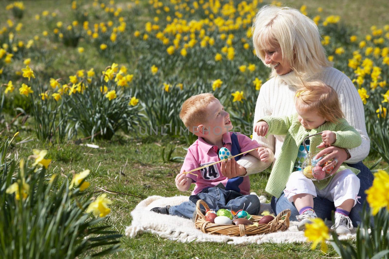 Mother And Children In Daffodil Field With Decorated Easter Eggs