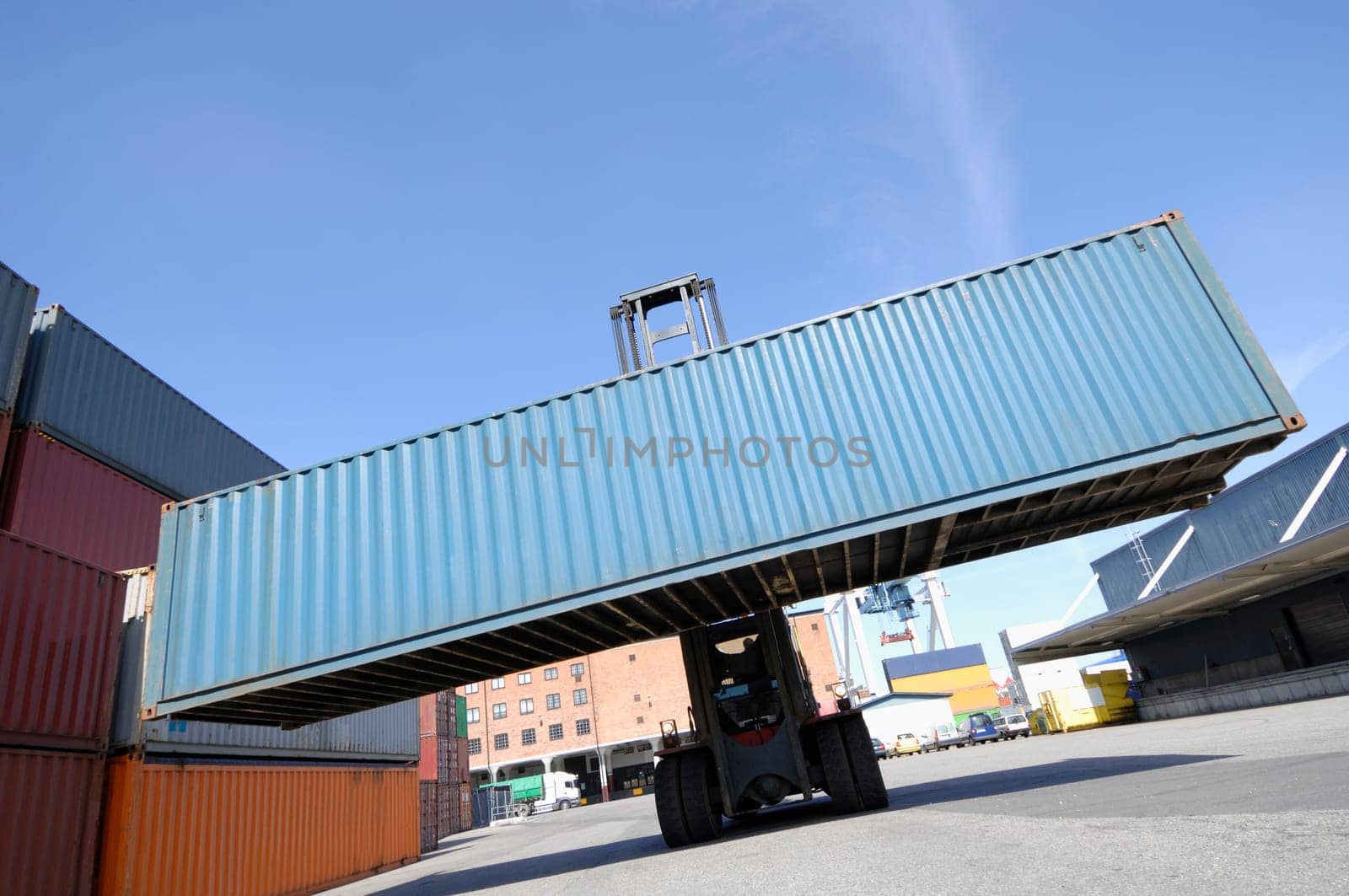 large forklift hoisting and stacking containers in busy container-port