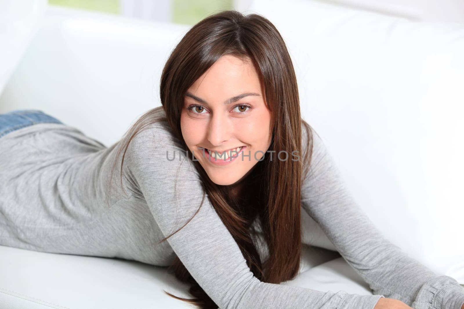 Smiling young woman laying on sofa
