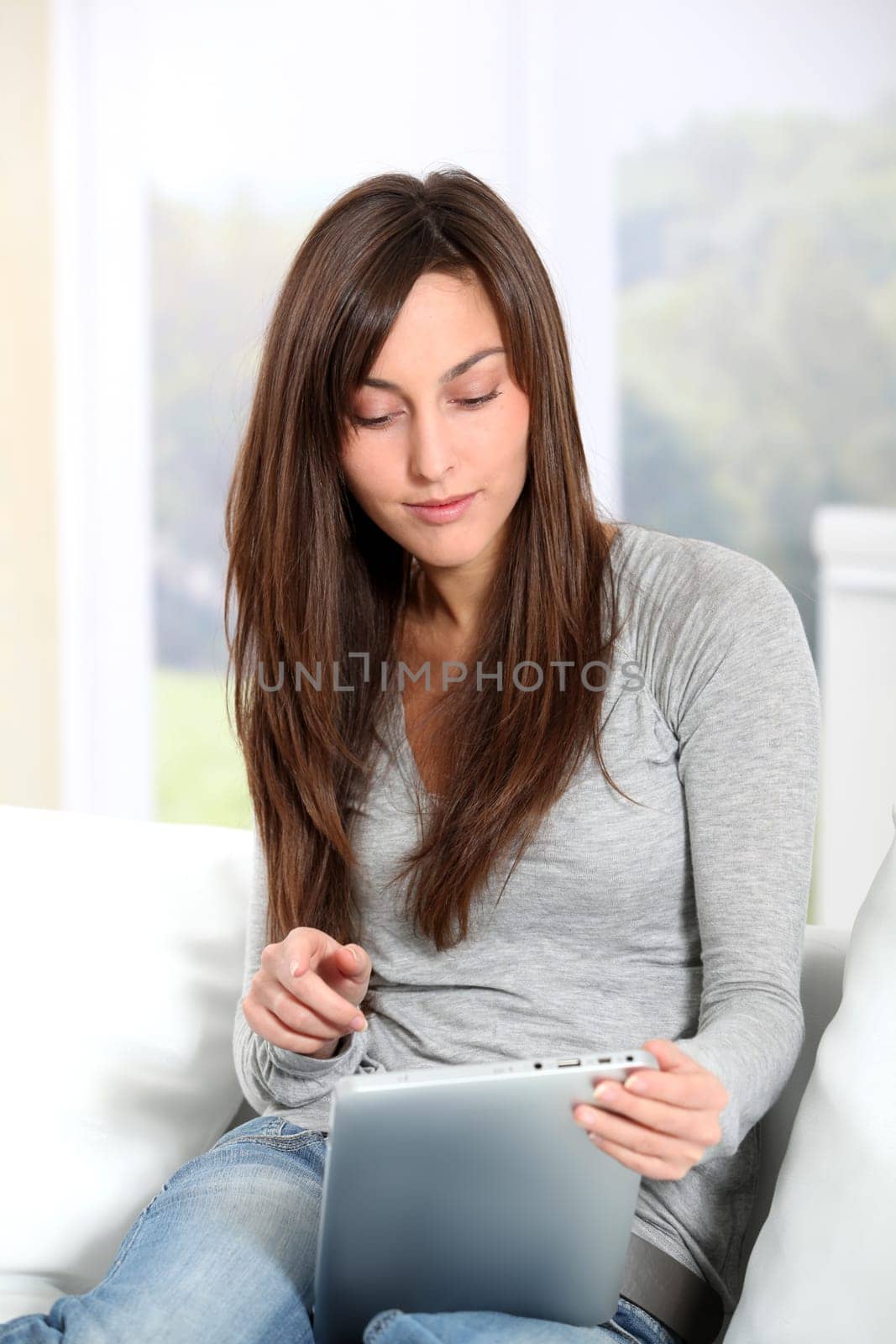 Young woman sitting on sofa with electronic pad