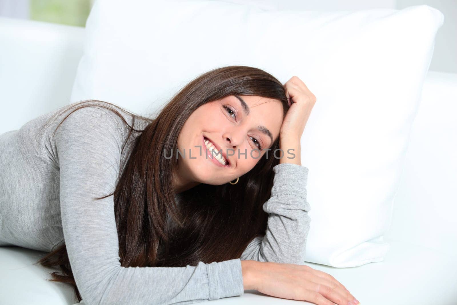 Smiling young woman laying on sofa