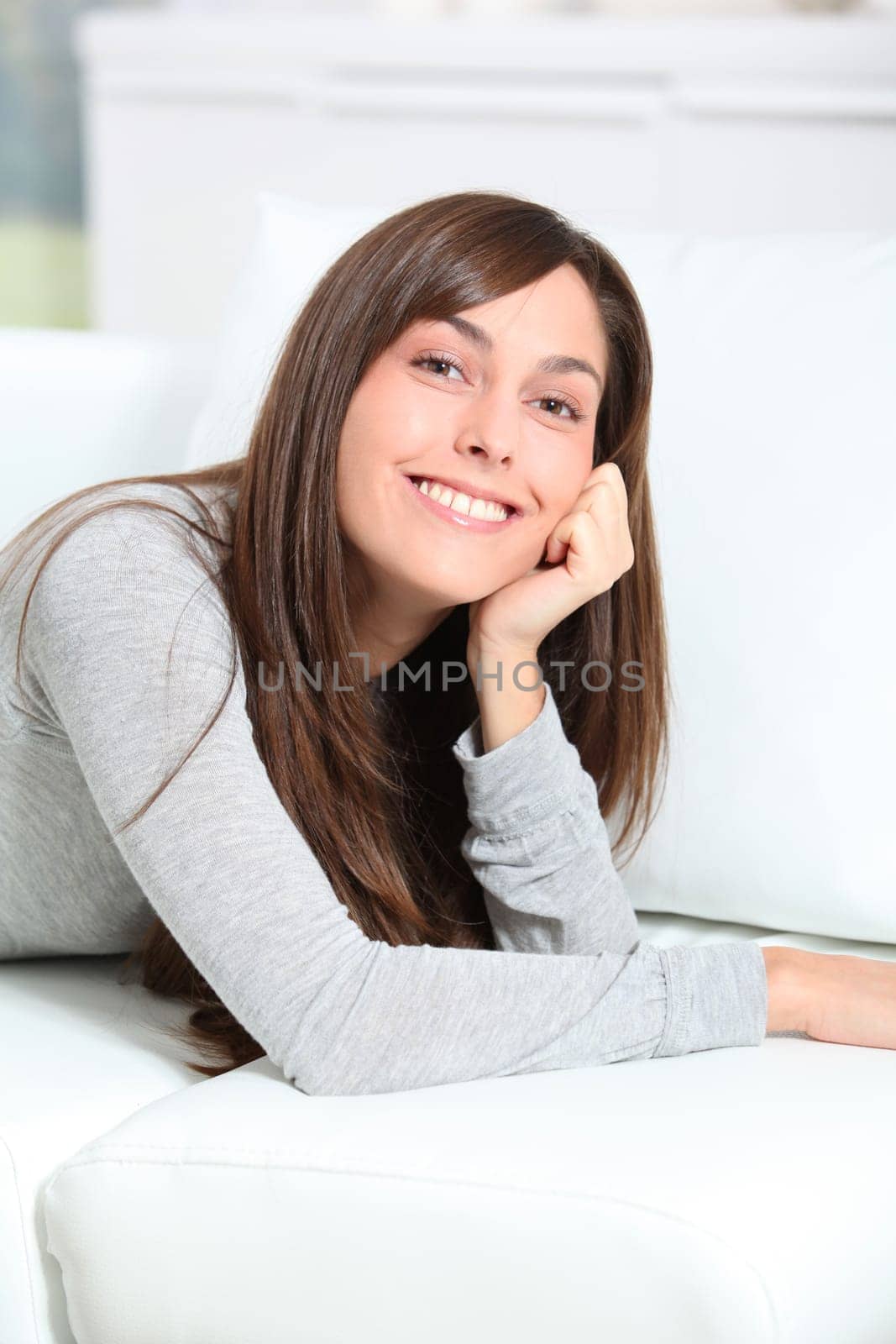Smiling young woman laying on sofa