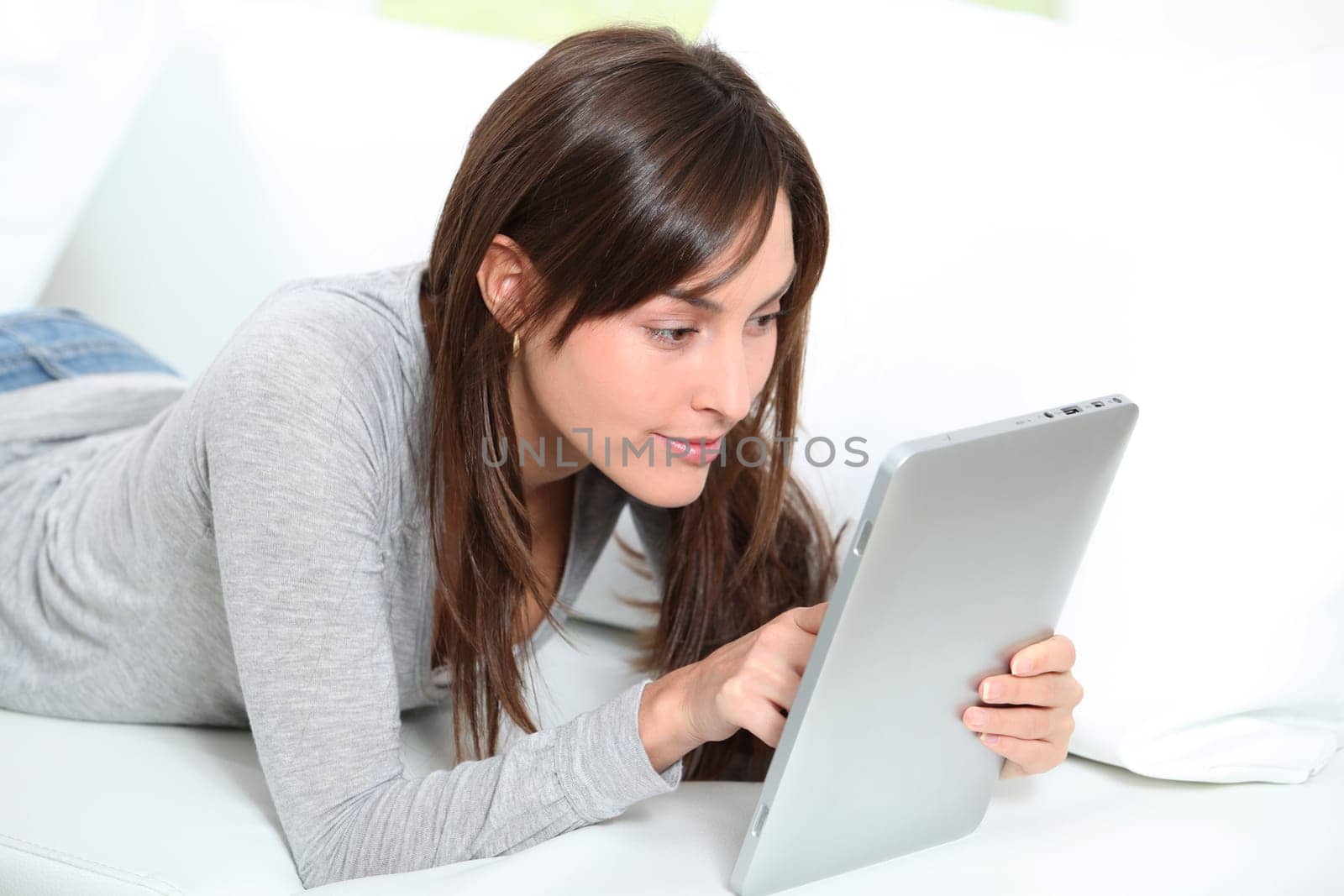 Young woman sitting on sofa with electronic pad