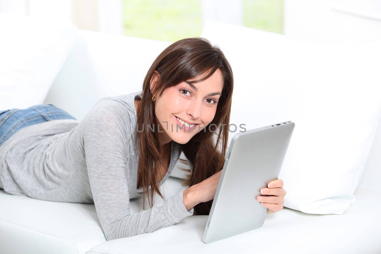 Young woman sitting on sofa with electronic pad