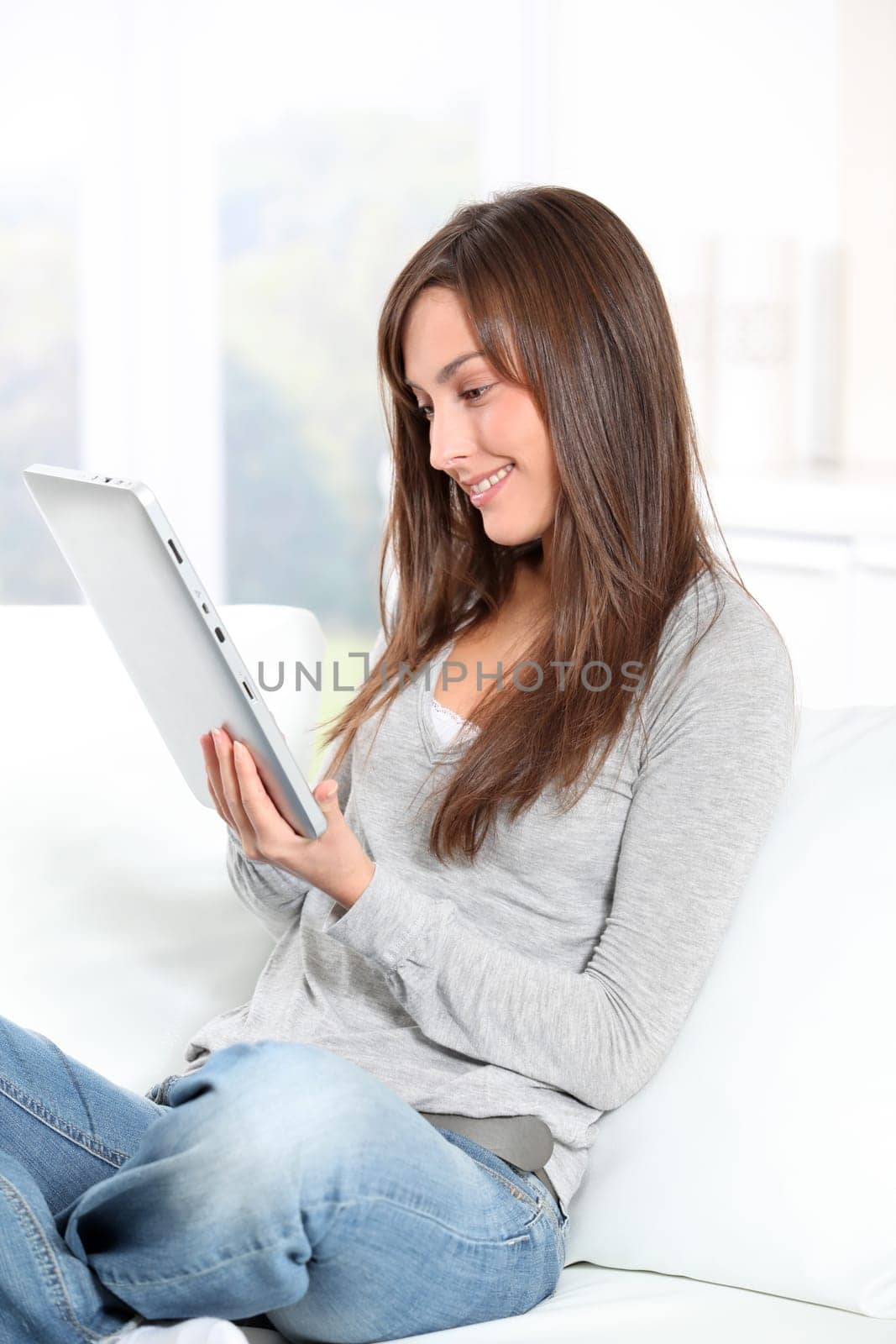 Young woman sitting on sofa with electronic pad