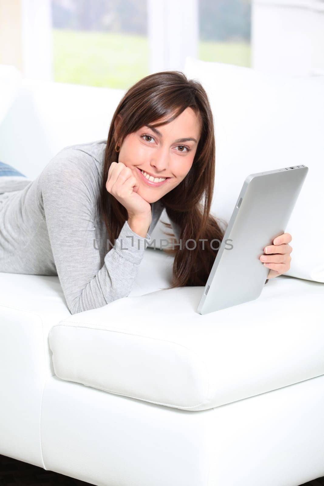 Young woman sitting on sofa with electronic pad
