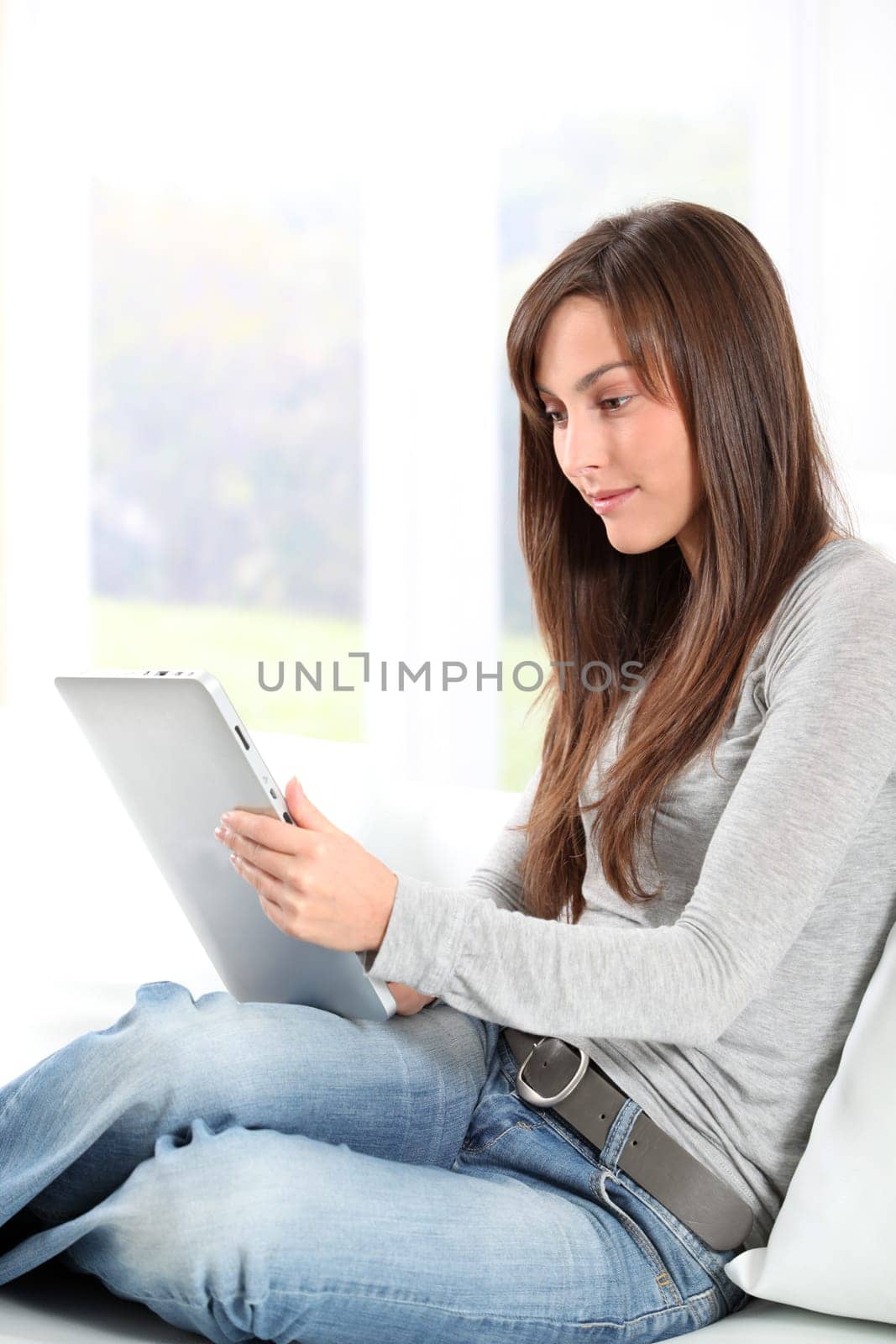 Young woman sitting on sofa with electronic pad
