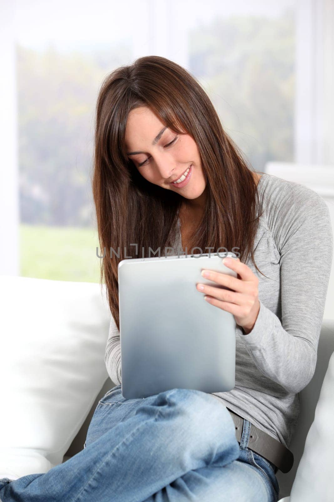 Young woman sitting on sofa with electronic pad