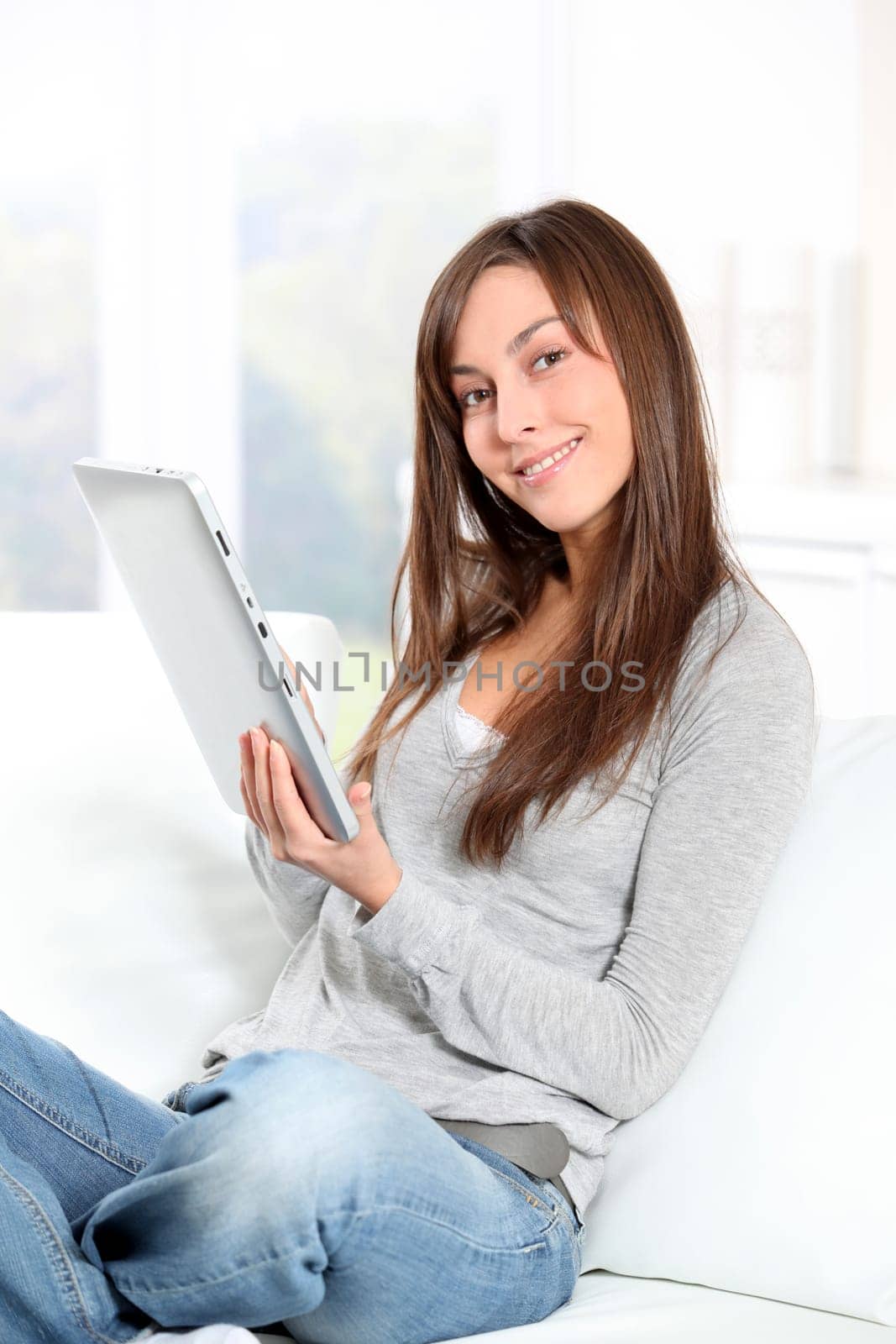 Young woman sitting on sofa with electronic pad