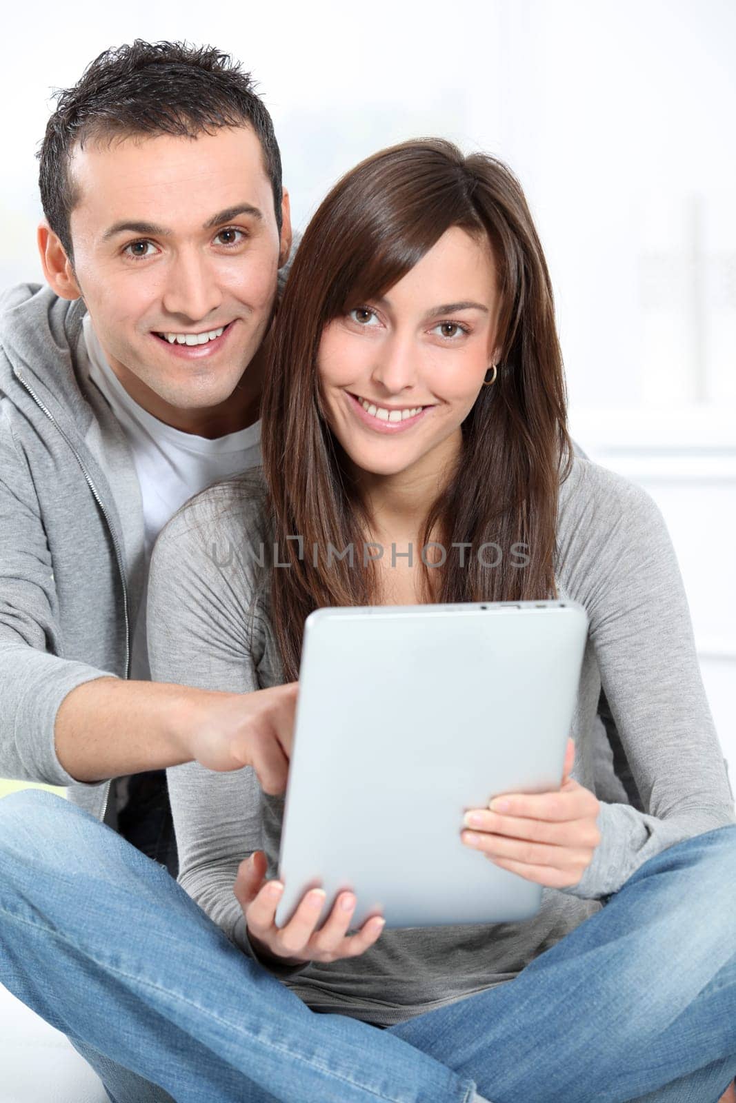 Young couple sitting on sofa with electronic pad