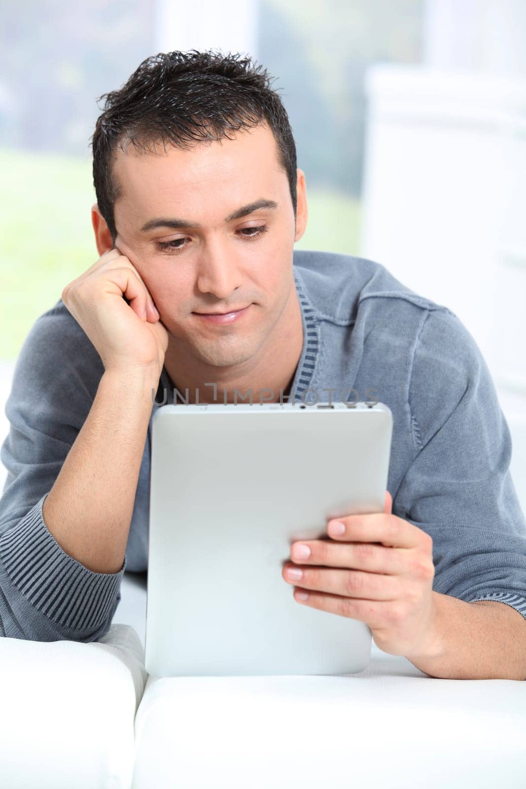 Young man sitting on sofa with electronic pad
