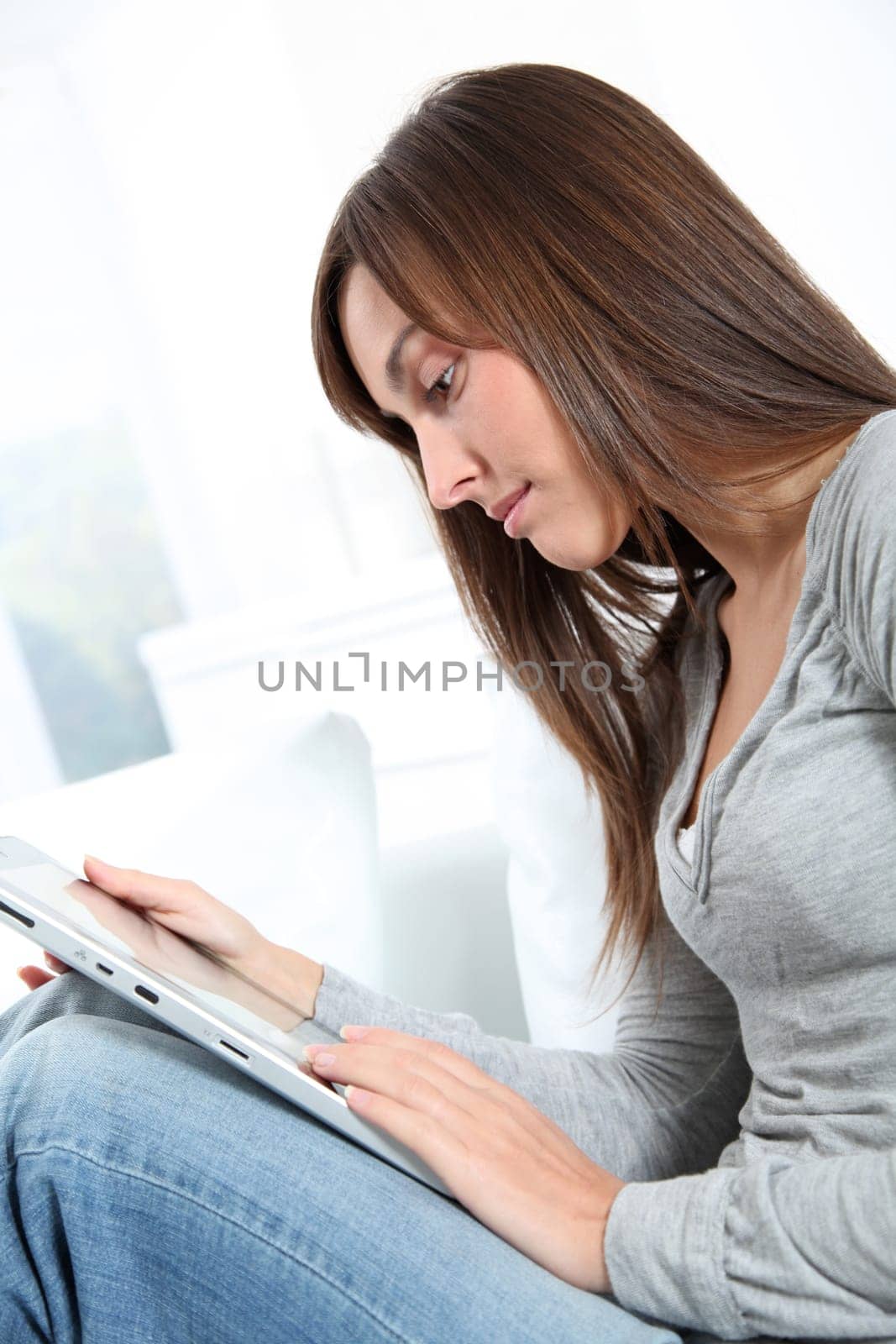 Young woman sitting on sofa with electronic pad