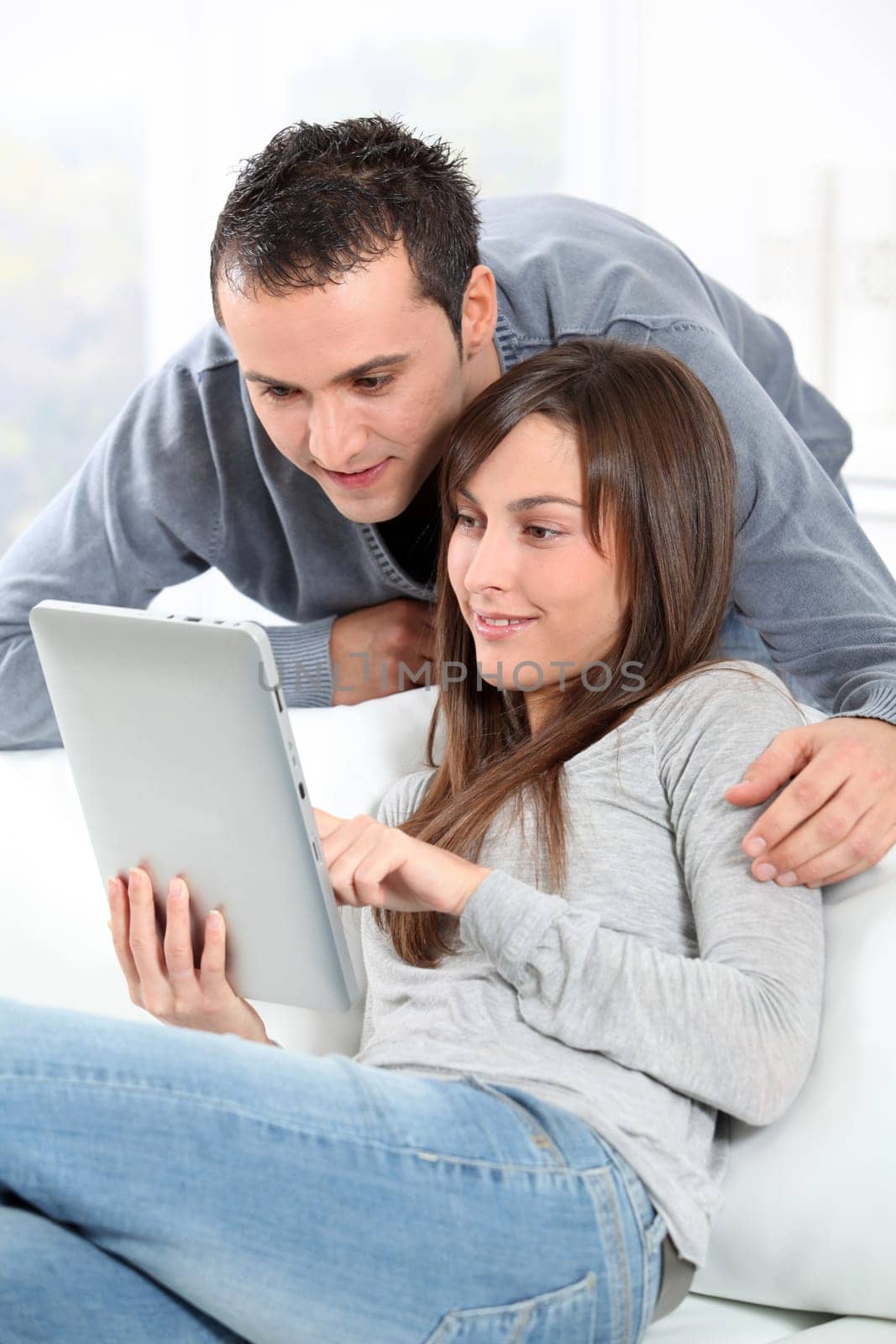Couple sitting on sofa with electronic pad