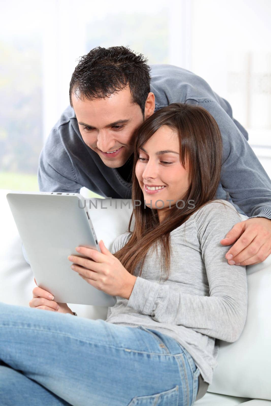 Couple sitting on sofa with electronic pad