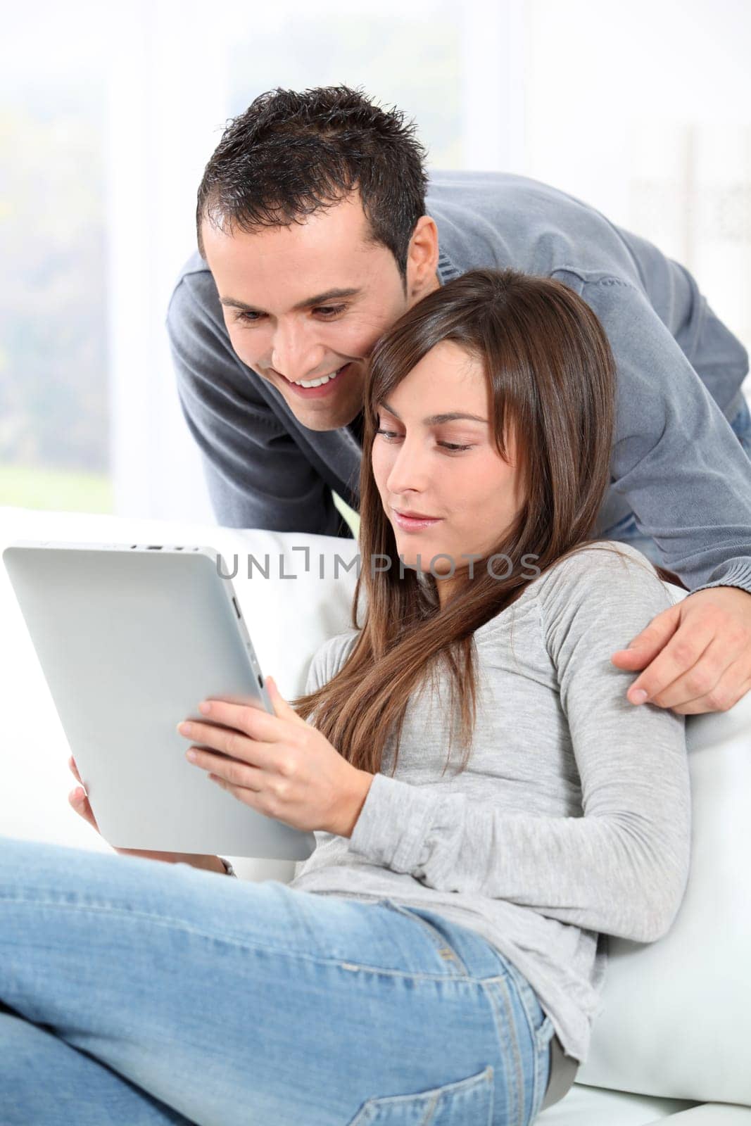 Couple sitting on sofa with electronic pad