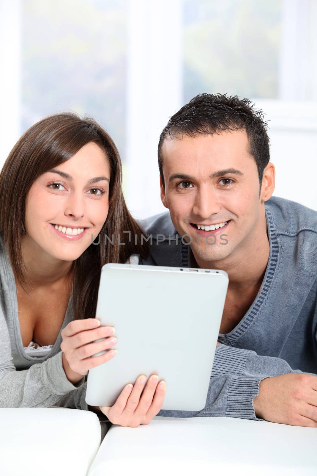 Couple sitting on sofa with electronic pad