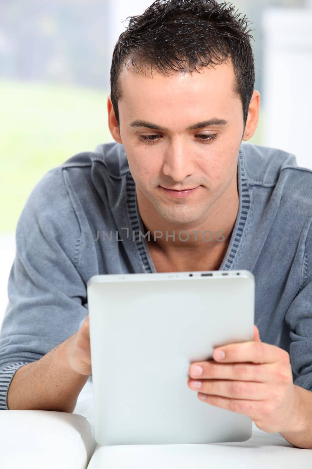 Young man sitting on sofa with electronic pad