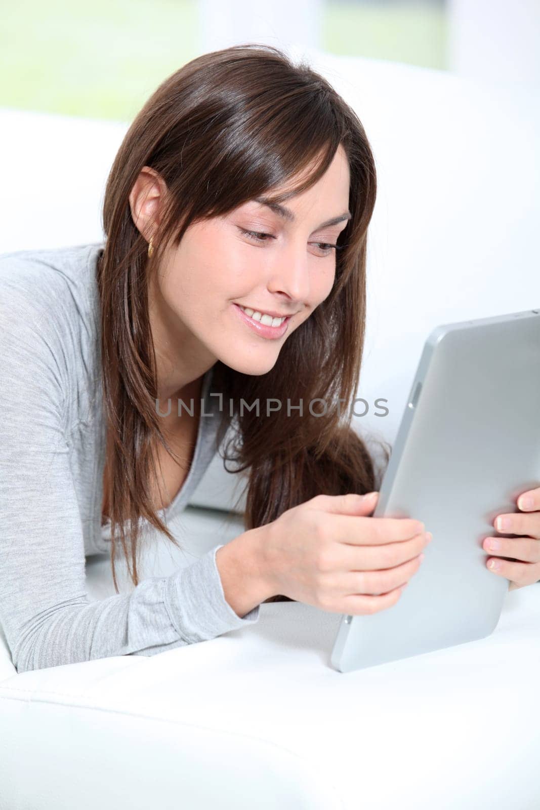 Young woman sitting on sofa with electronic pad