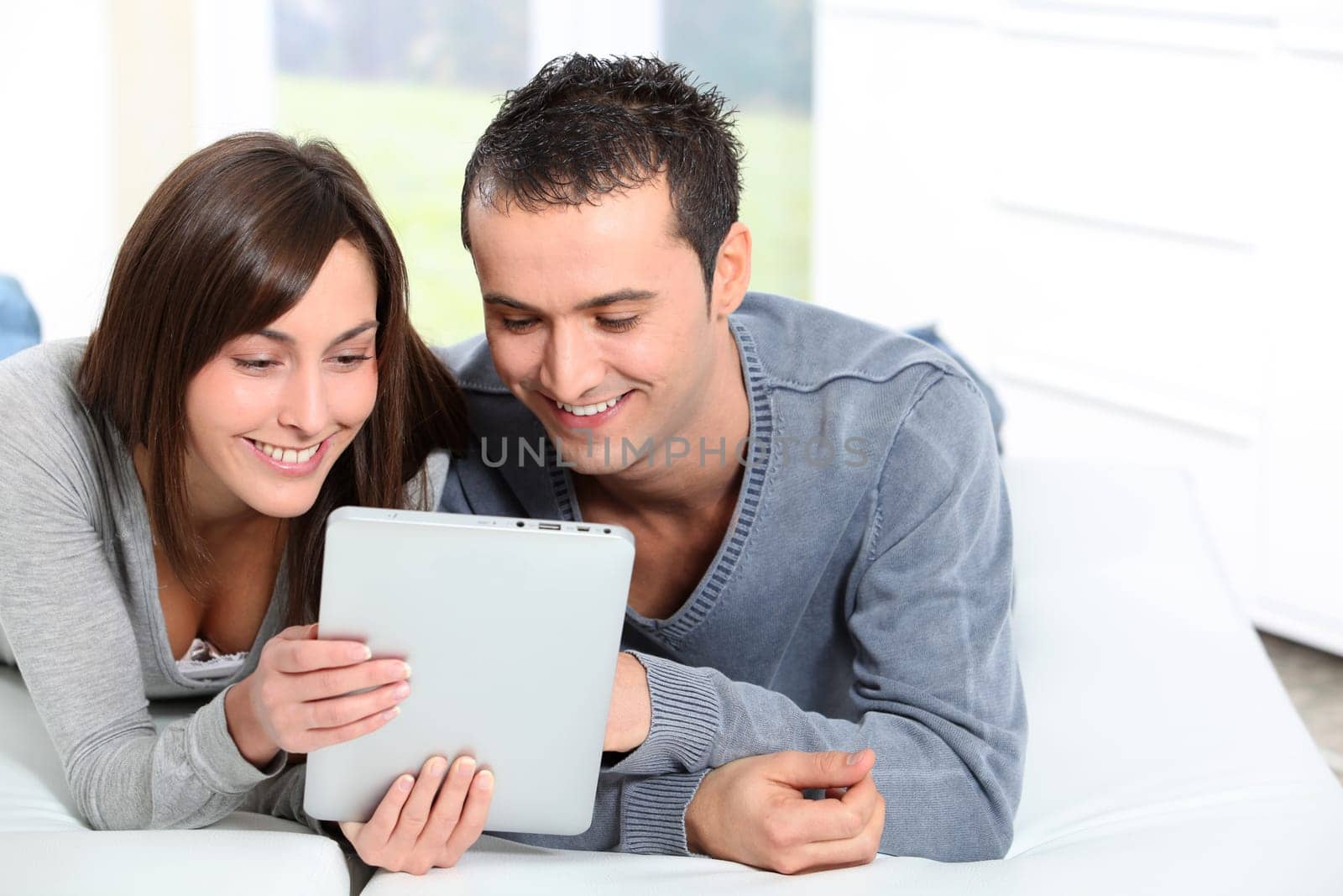 Couple sitting on sofa with electronic pad