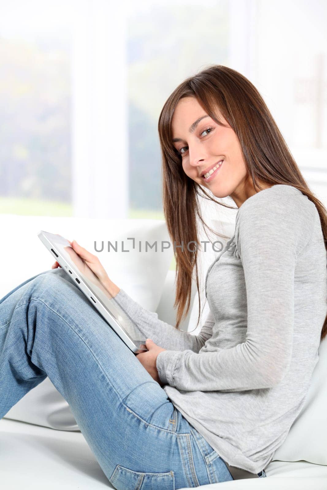 Young woman sitting on sofa with electronic pad