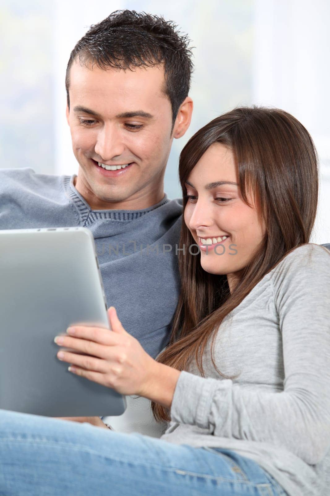 Couple sitting on sofa with electronic pad