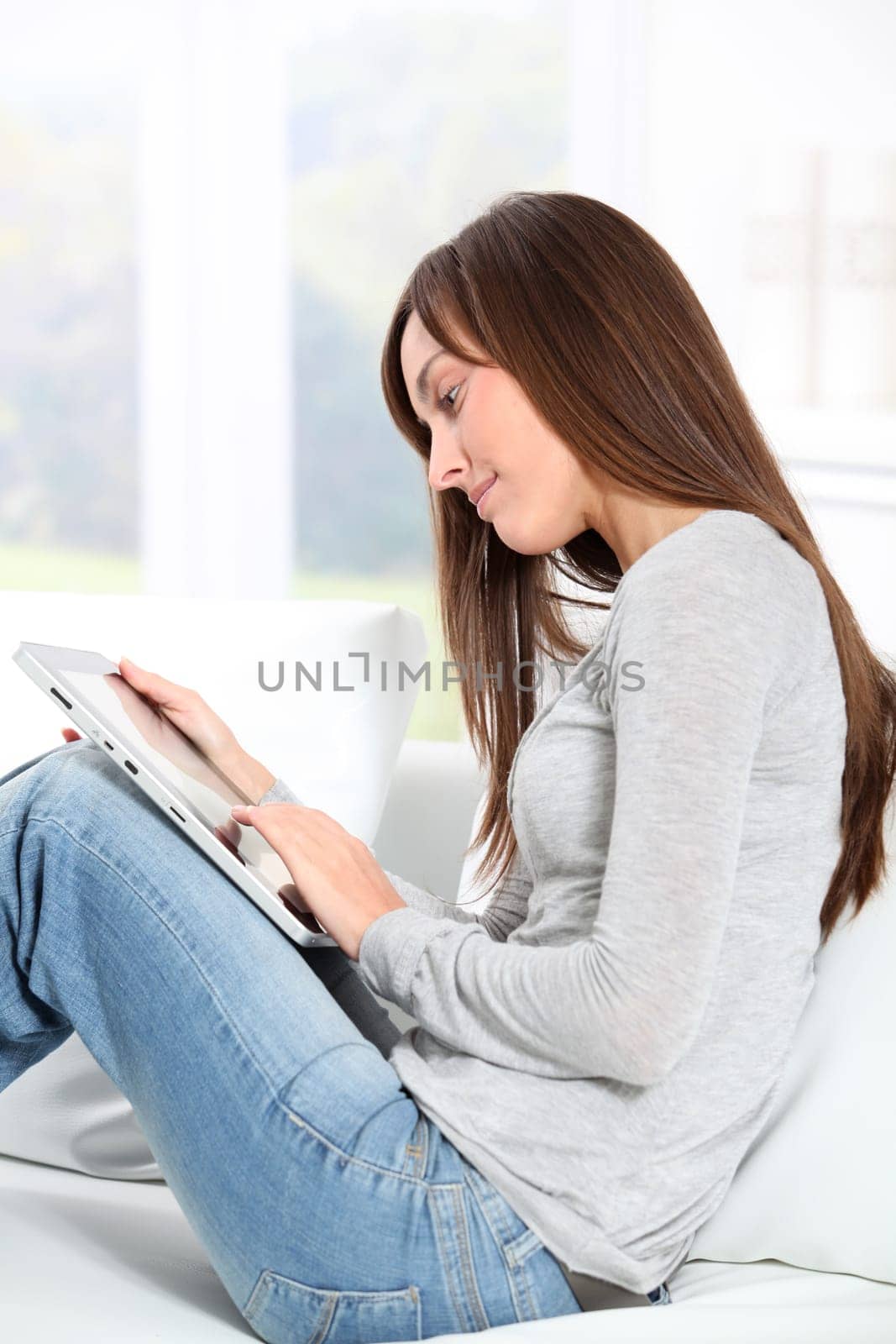 Young woman sitting on sofa with electronic pad
