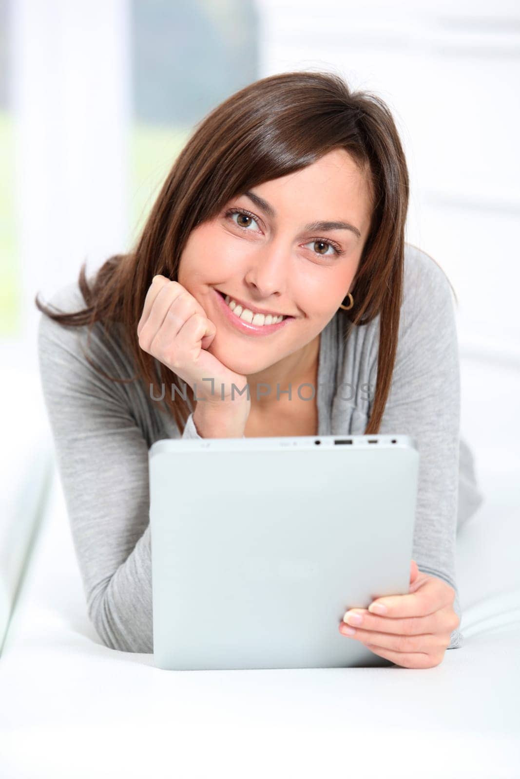 Young woman laying on sofa with electronic pad