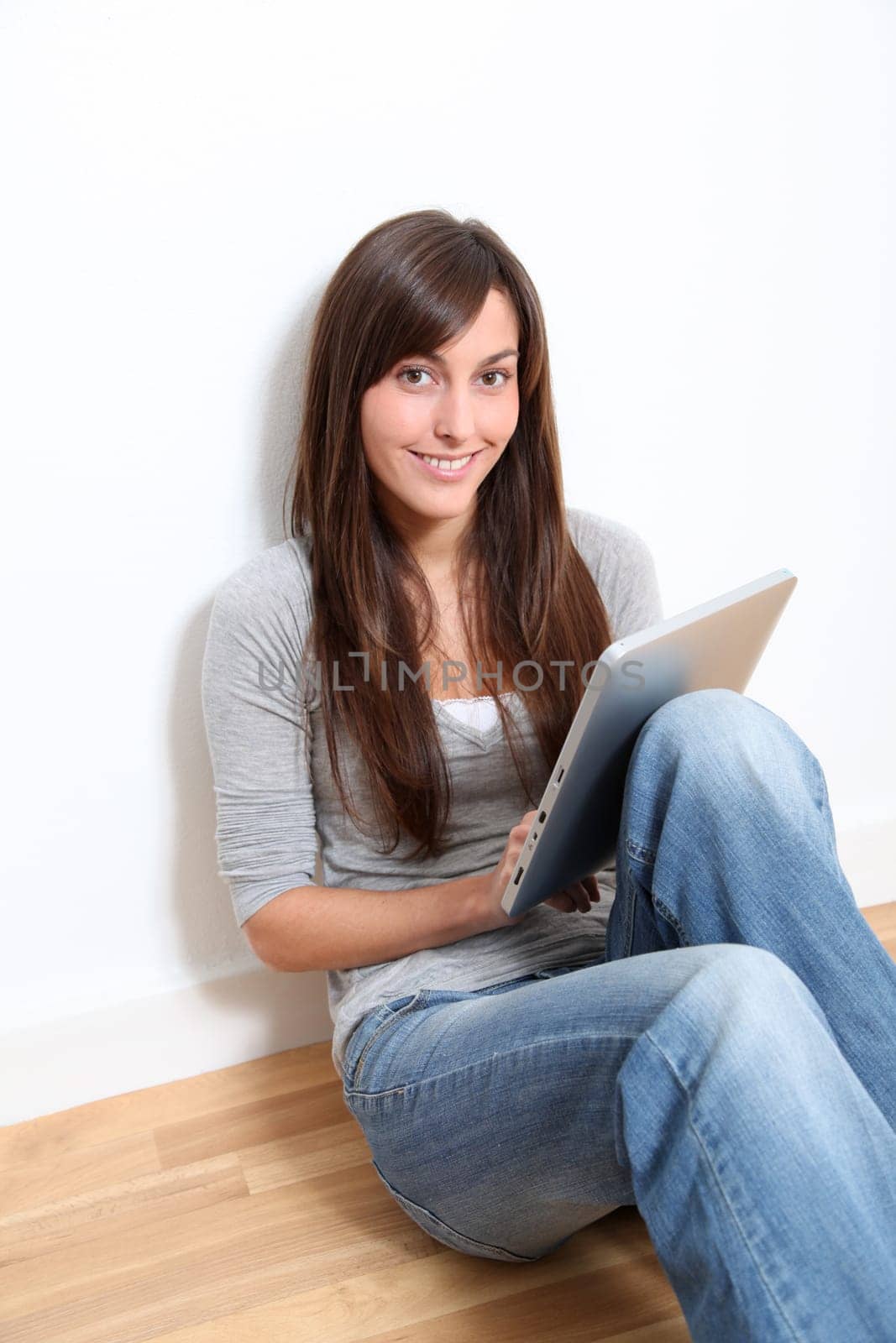 Young woman sitting on the floor with electronic pad