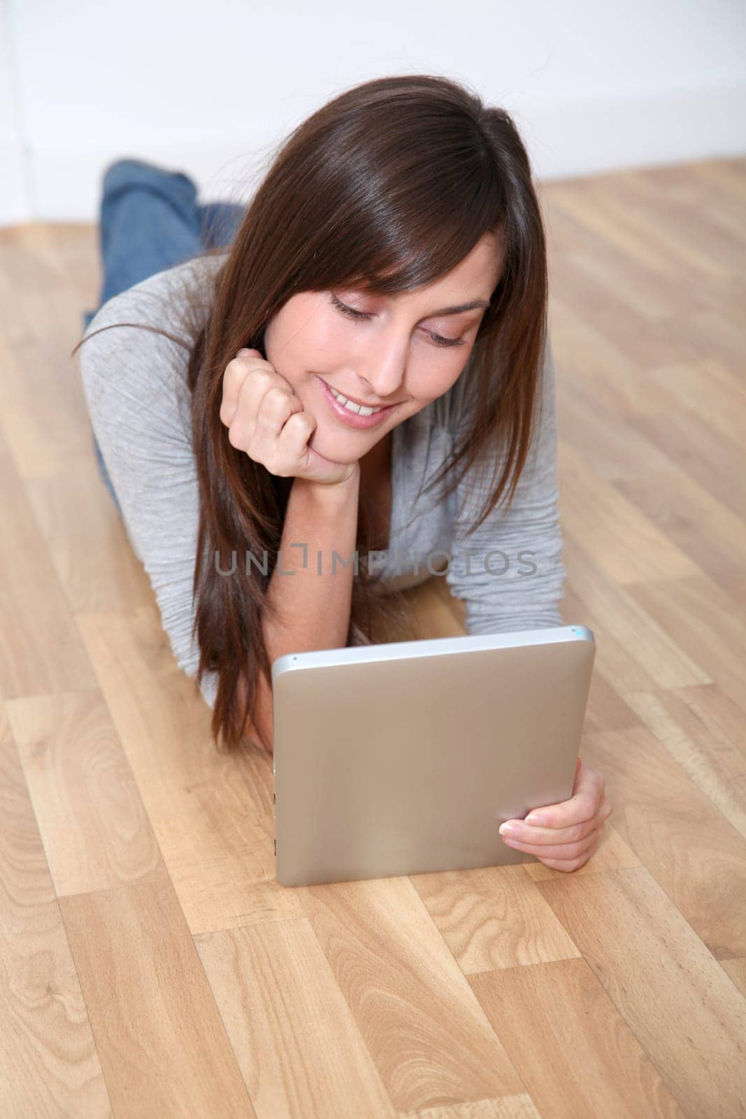 Young woman laying down the floor with electronic pad