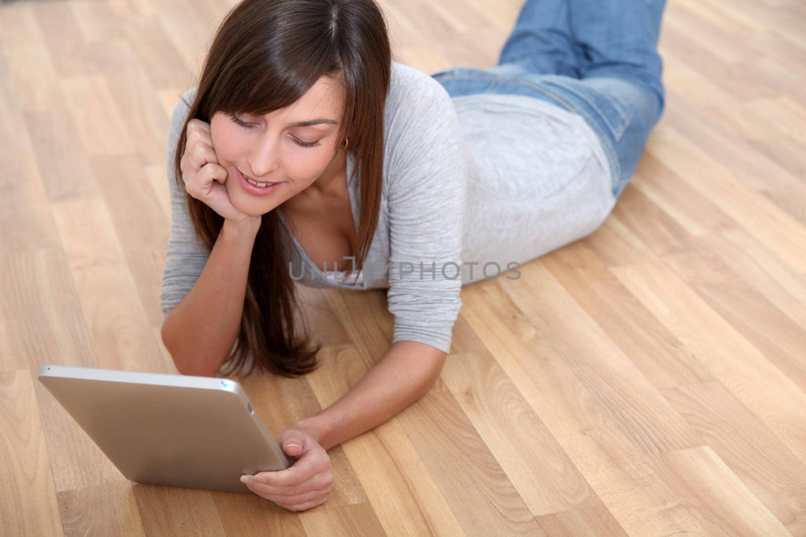 Young woman laying down the floor with electronic pad