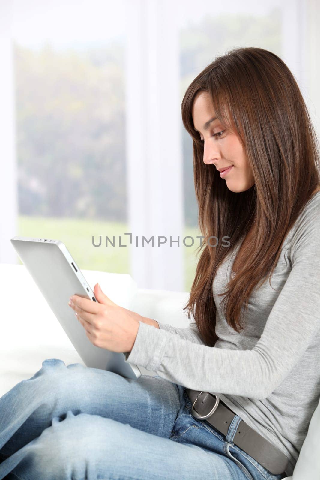 Young woman sitting on sofa with electronic pad