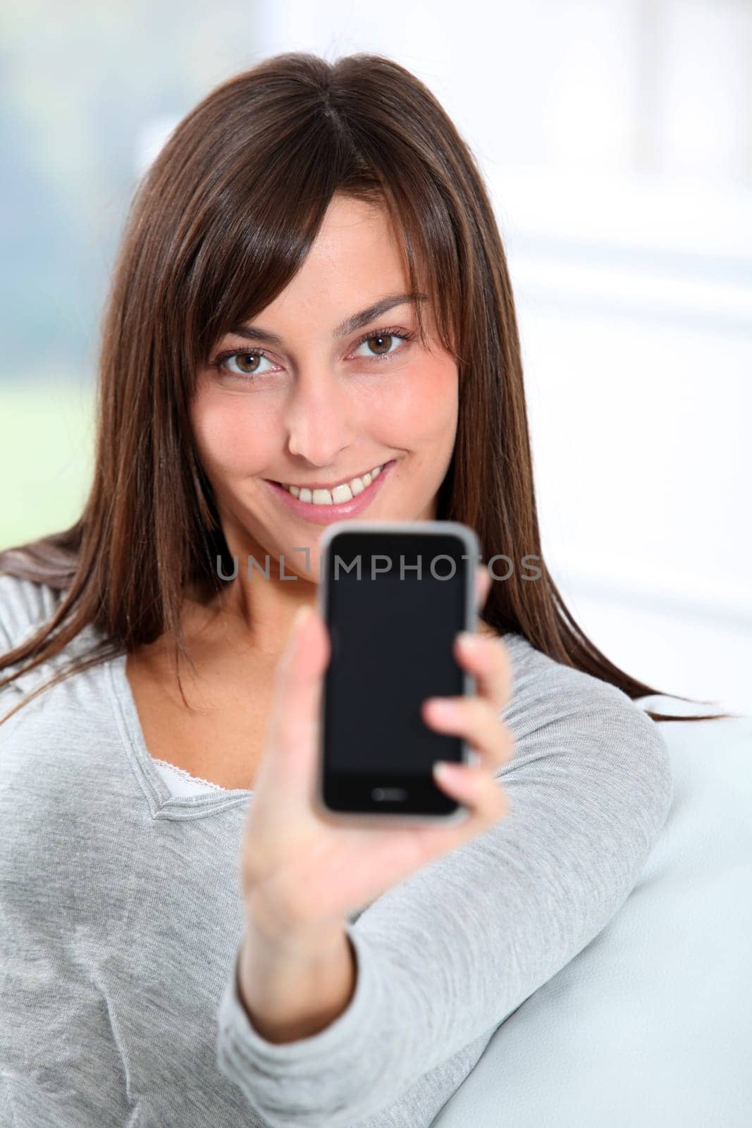Beautiful young woman showing mobile phone