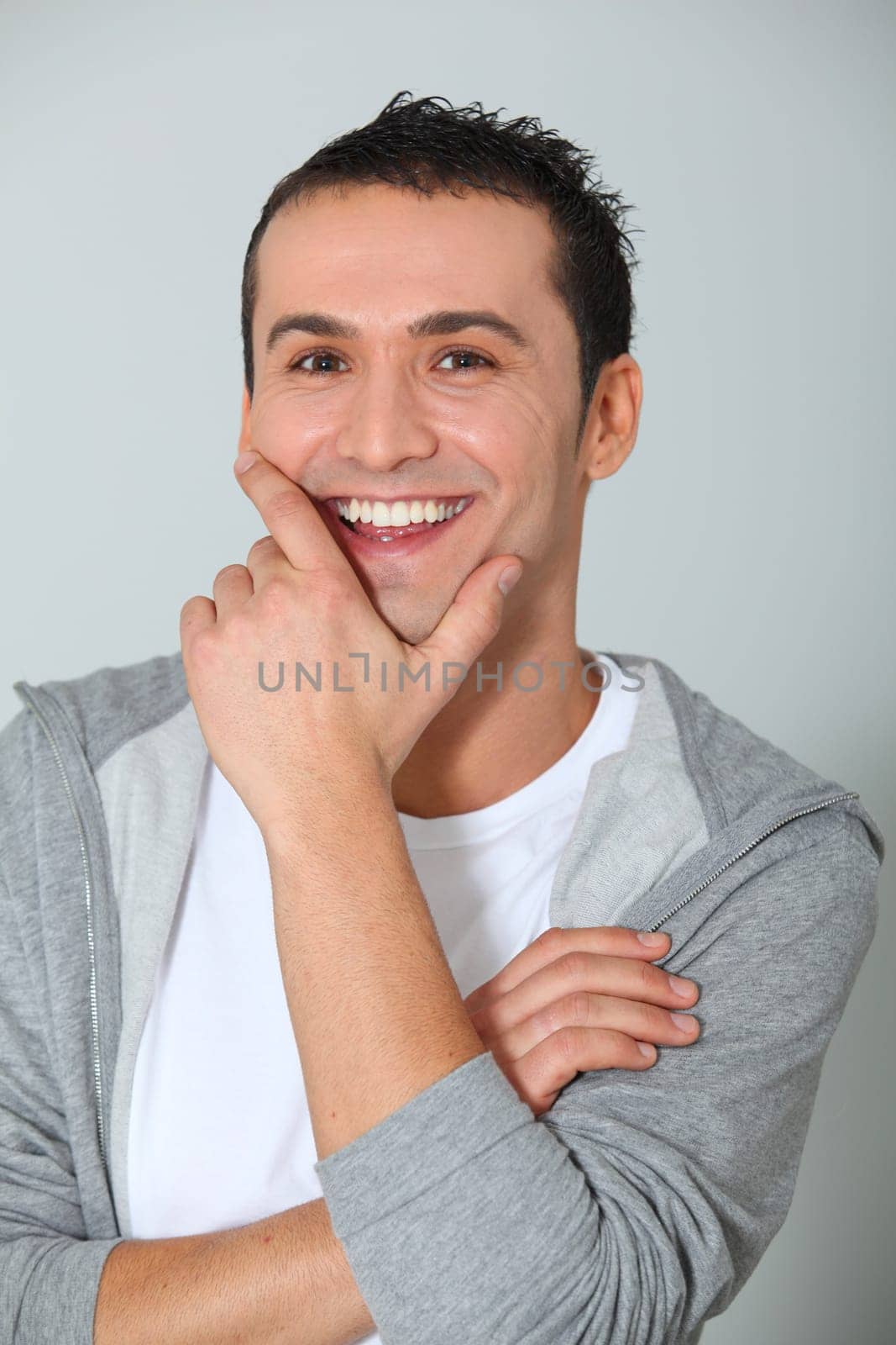 Closeup of young man smiling with hand on chin
